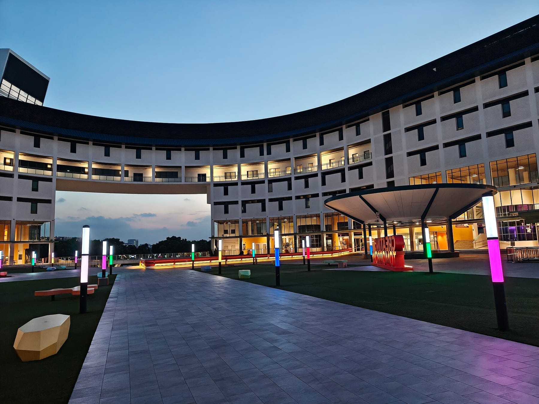 Curved campus building and lit courtyard at dusk