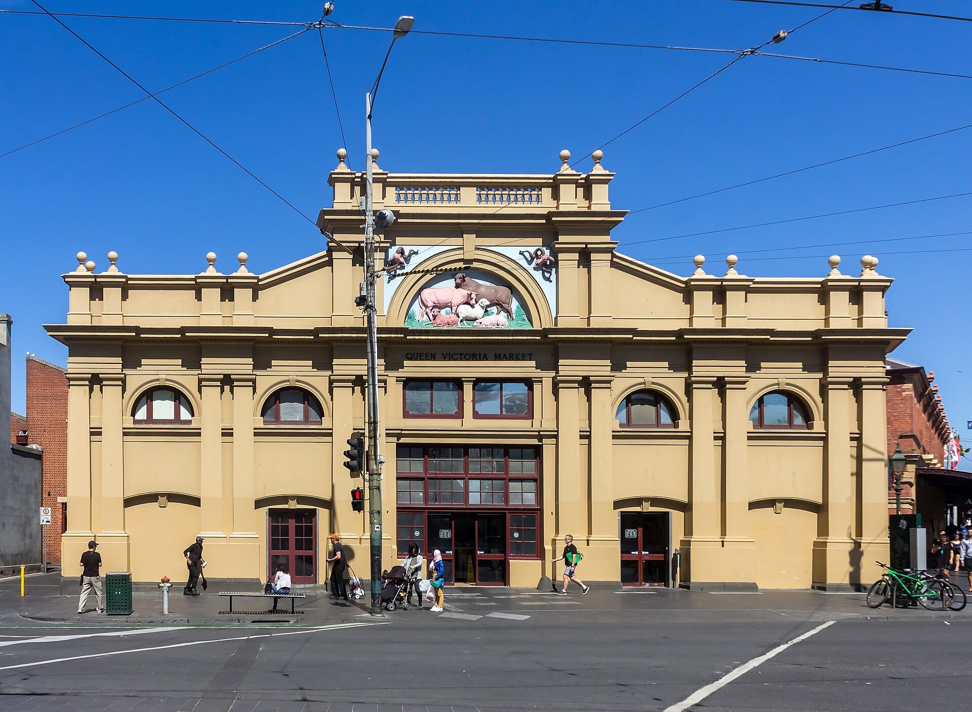 The ochre-coloured heritage facade of Queen Victoria Market in Melbourne under a clear blue sky